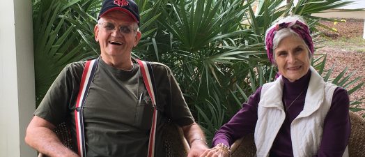 A husband and wife sitting together laughing and smiling.