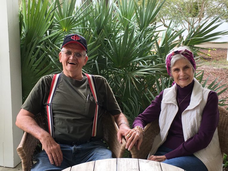 A husband and wife sitting together laughing and smiling.