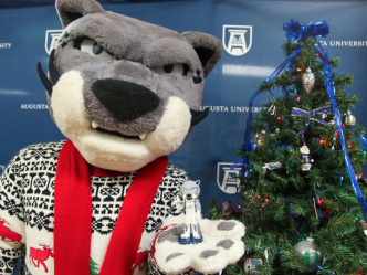 Augustus the mascot standing next to a Christmas tree