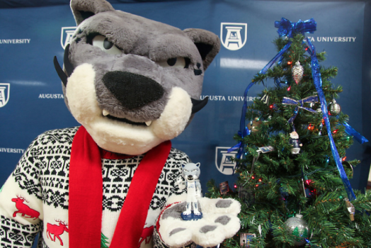 Augustus the mascot standing next to a Christmas tree