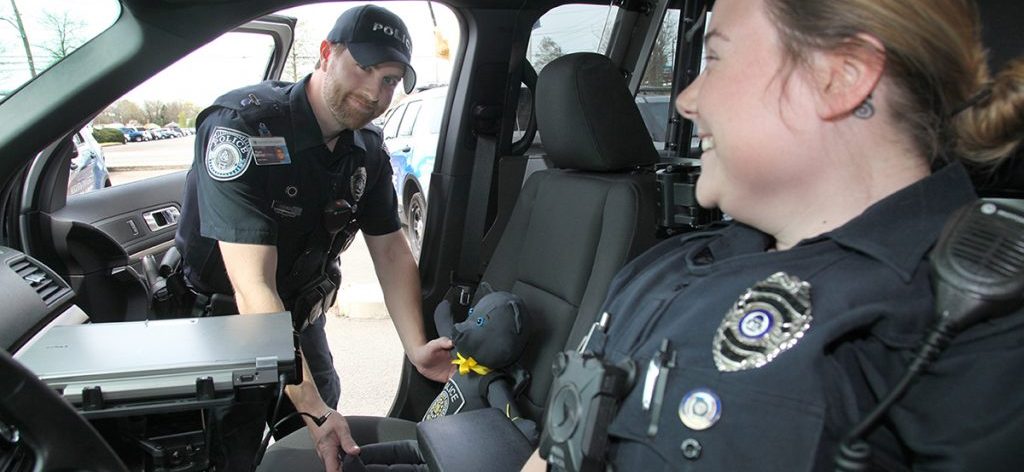 A male and female officers sitting in a cop car.