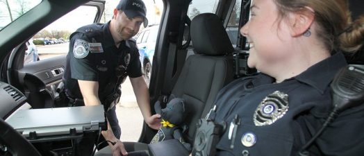 A male and female officers sitting in a cop car.