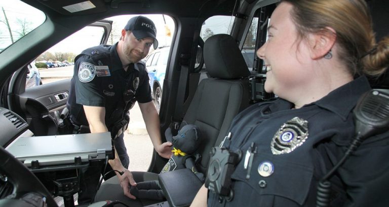 A male and female officers sitting in a cop car.