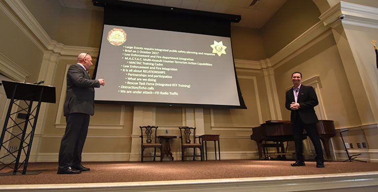Two men on a stage with a screen