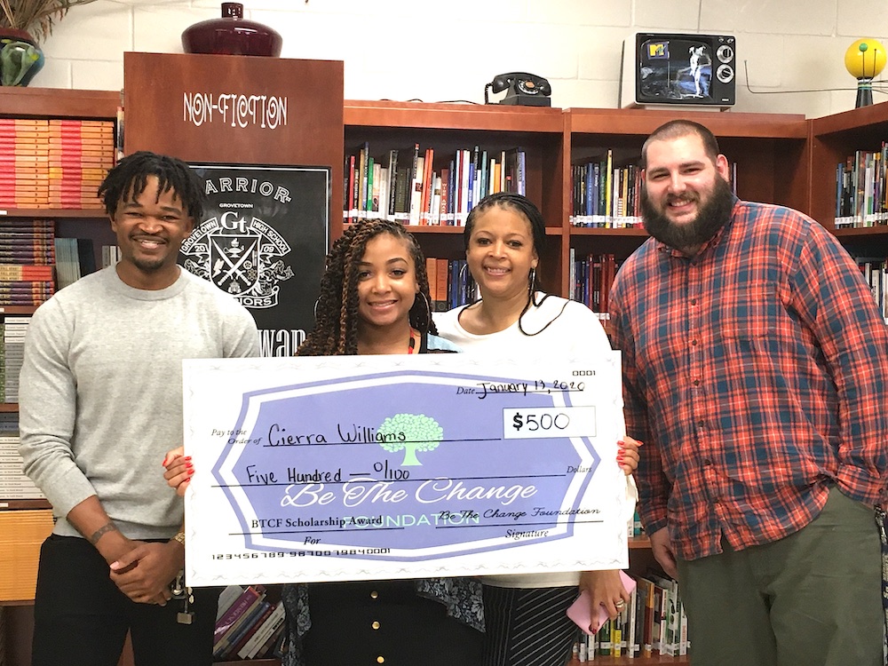 people smiling holding big check