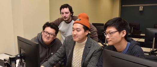 Four men looking at a computer