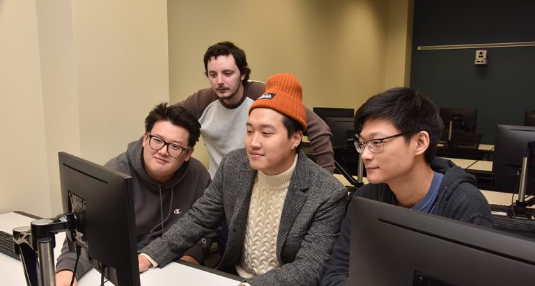 Four men looking at a computer