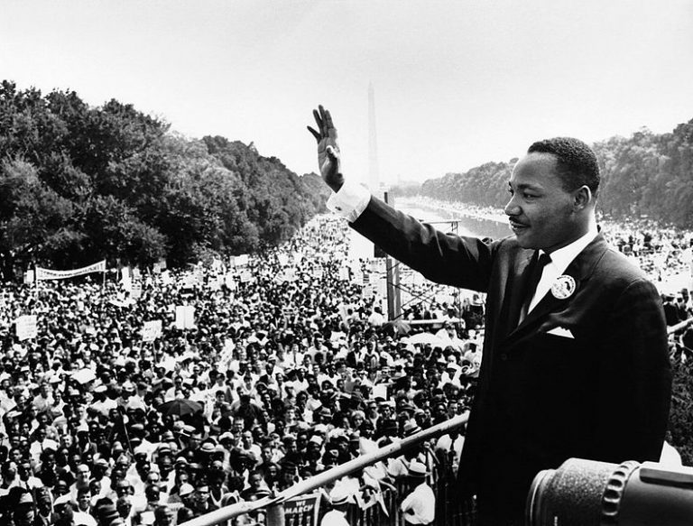 black and white photo of a man waving to a crowd full of people