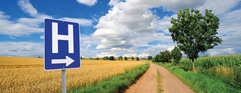 A picture of a hospital sign in front of a corn field.
