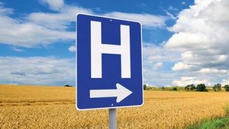 A picture of a hospital sign in front of a corn field.