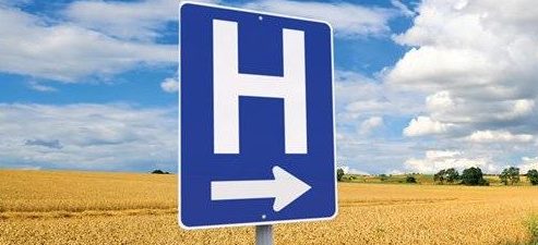 A picture of a hospital sign in front of a corn field.