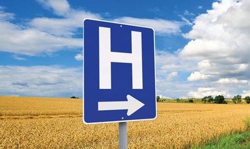 A picture of a hospital sign in front of a corn field.