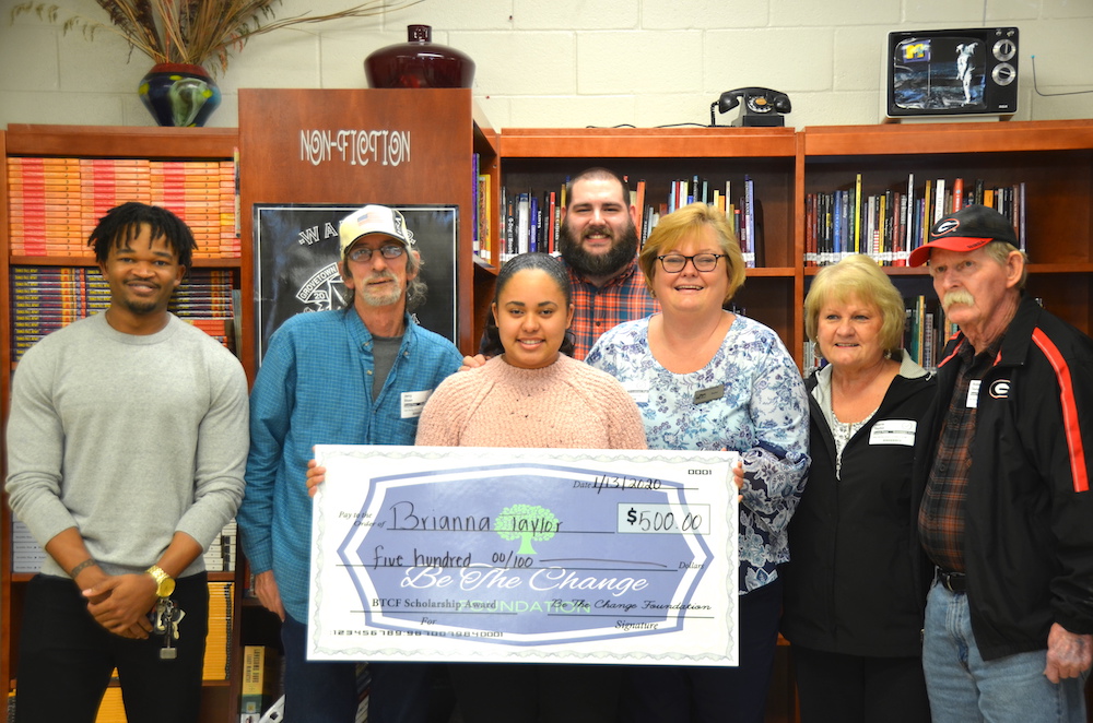 people smiling while holding big check