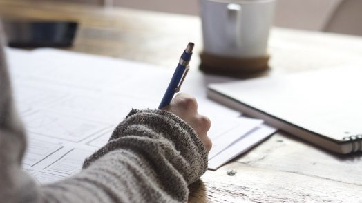 hand holding a pen writing things down on a piece of paper