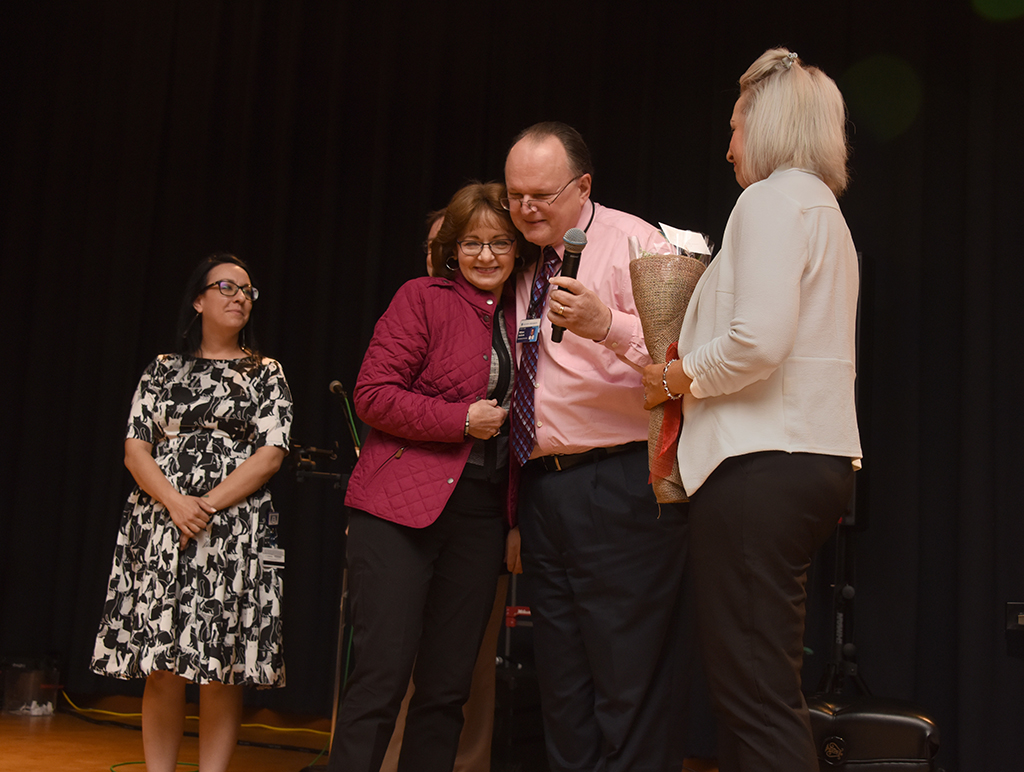 Man hugs woman with two women looking on