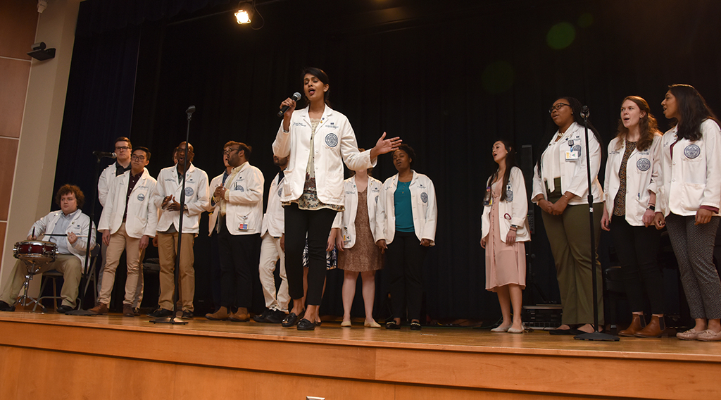 Woman singing with a group of people behind her