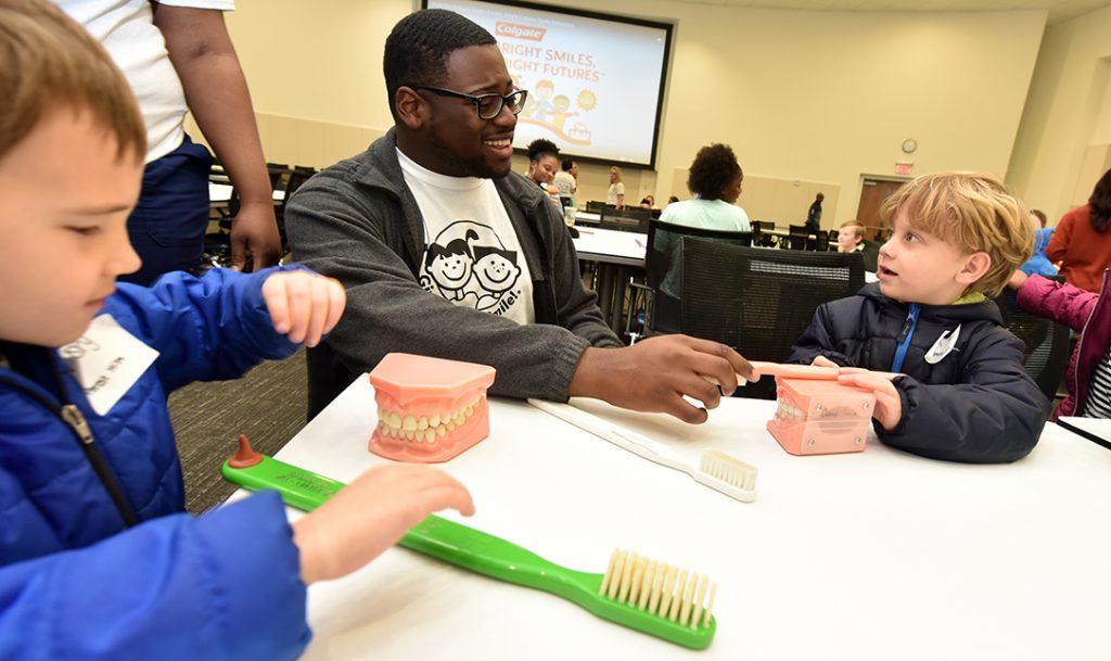 Man watches students practice brushing