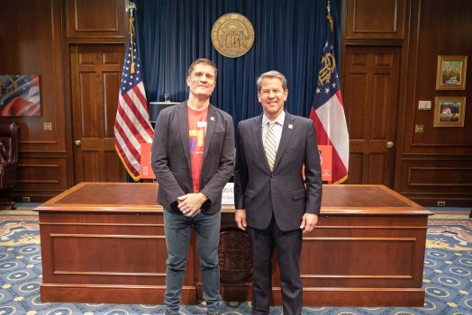 Governor Brian Kemp stands next to the executive director of Paceline Ride