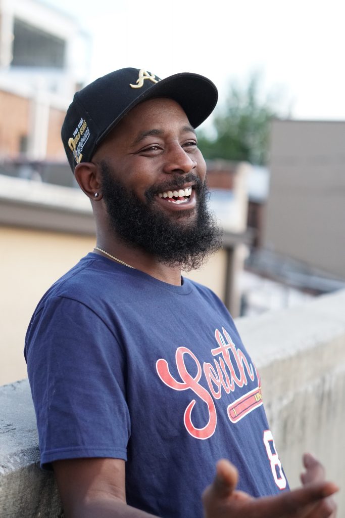 image of man smiling in a blue T-shirt and black cap