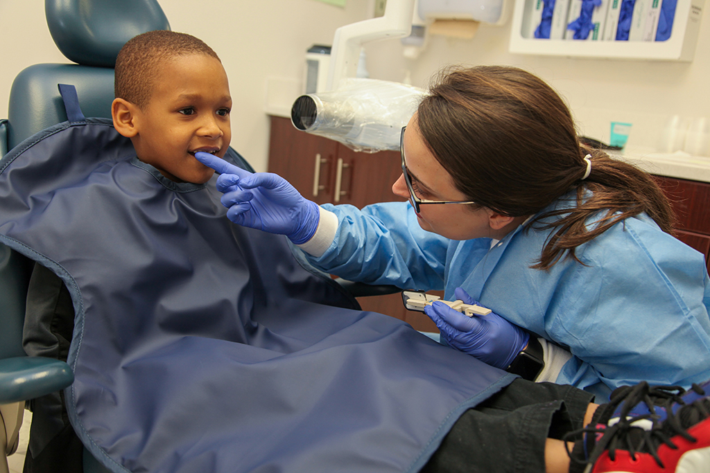 Woman showing boy how to take care of teeth