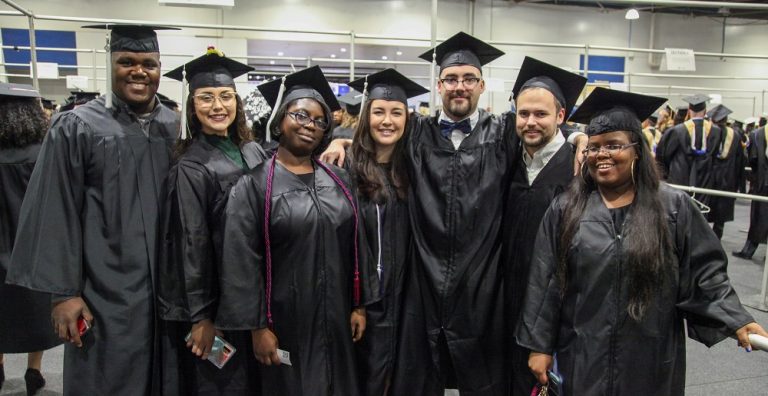group of 7 graduates in black caps and gowns