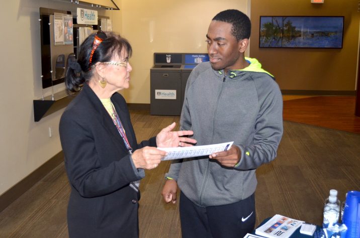 Woman holding a piece of paper talking with a young adult