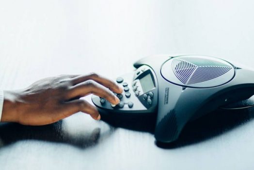 hand on conference phone speaker