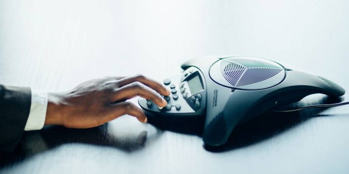 hand on conference phone speaker