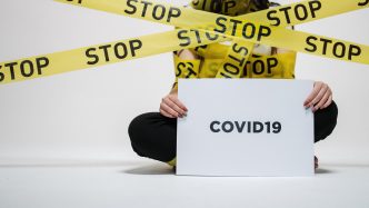 person wrapped in a sign that says stop holding another sign that reads COVID19
