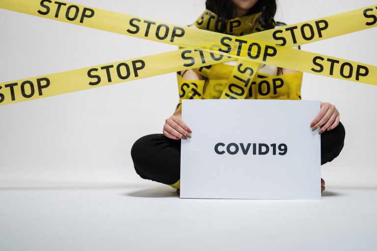 person wrapped in a sign that says stop holding another sign that reads COVID19