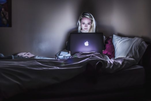 Woman looking her laptop while in bed.