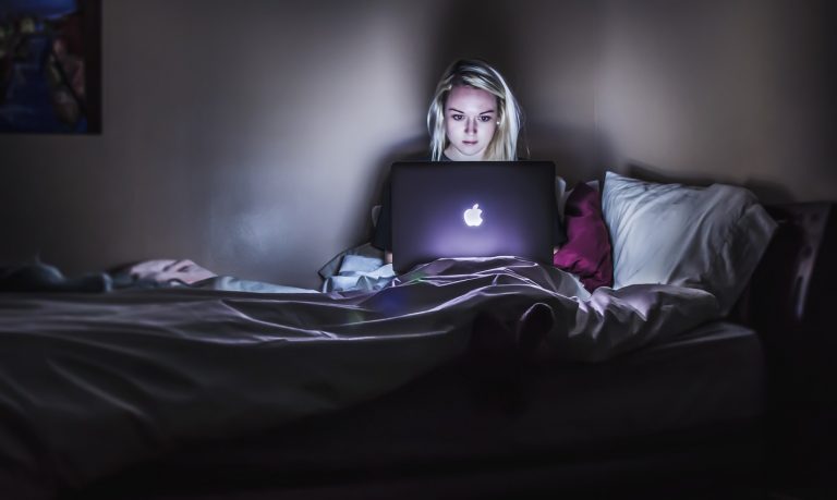 Woman looking her laptop while in bed.
