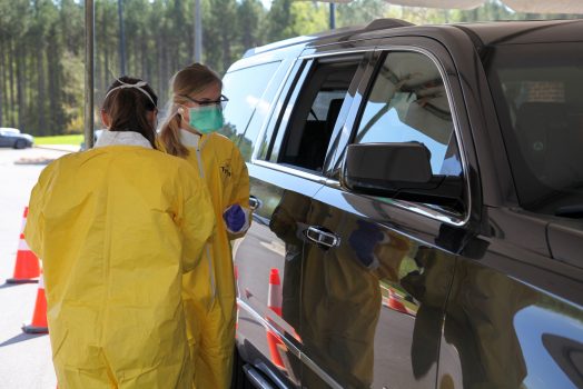two nurses giving test near a car