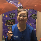 woman in blue scrubs holding sign that says Hocus Pocus