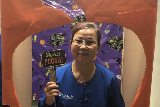 woman in blue scrubs holding sign that says Hocus Pocus