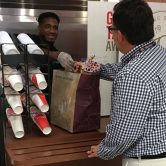 Man reaching across counter for grocery brown bag
