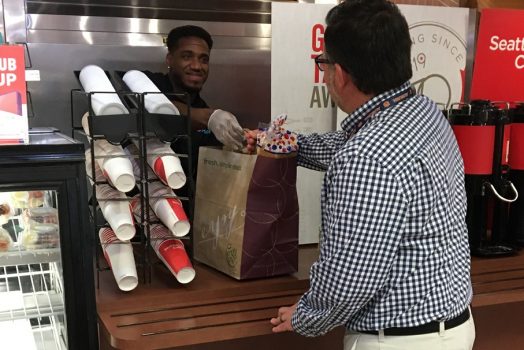 Man reaching across counter for grocery brown bag