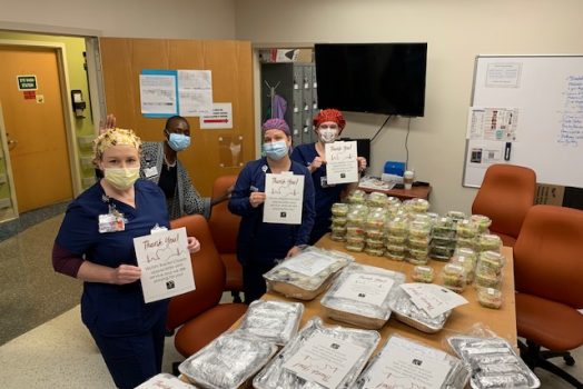 three women holding signs with food