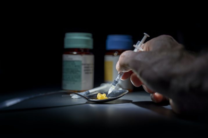 Person putting a needle in a drug