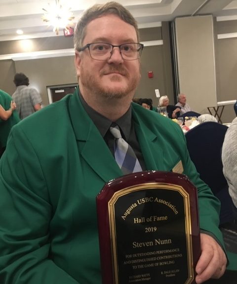 man in green sport coat with award