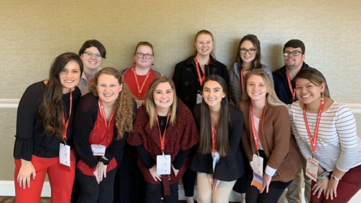 11 students posing for a photo at a conference