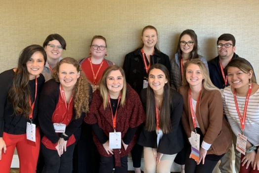 11 students posing for a photo at a conference