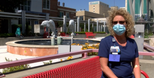 Nurse on red bench wearing mask and blue scrubs