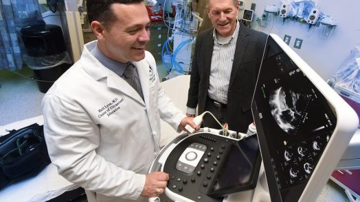 Two men looking at a portable ultrasound machine