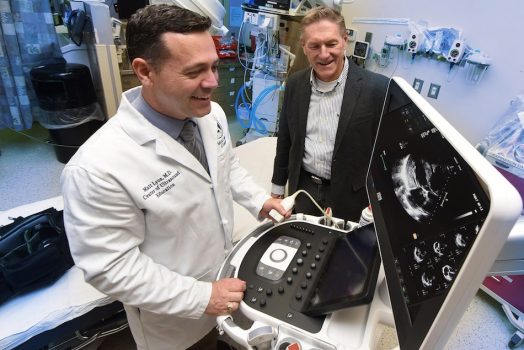 Two men looking at a portable ultrasound machine