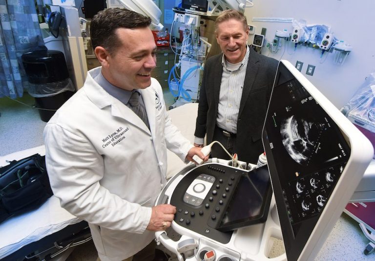 Two men looking at a portable ultrasound machine