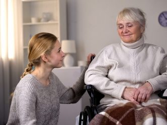 Young woman kneeling next to older woman in wheelchair