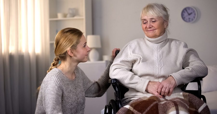 Young woman kneeling next to older woman in wheelchair