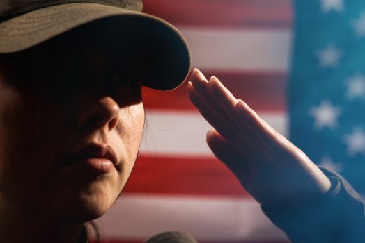 Woman saluting in front of flag