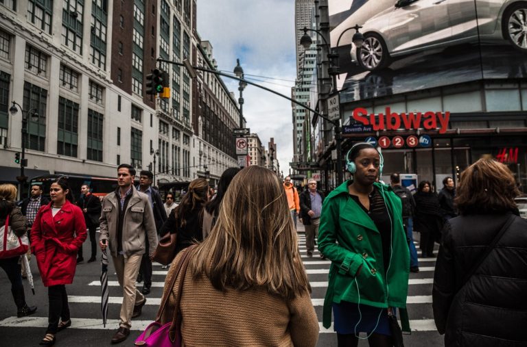 A crowd of people walking through an intersection.